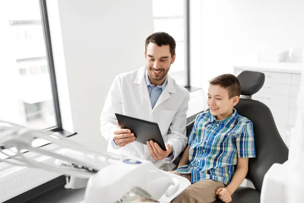 Dentista mostrando tablet pc para paciente criança na clínica — Fotografia de Stock