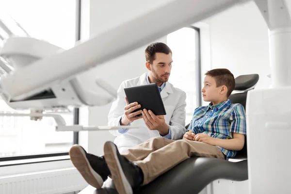 Dentista mostrando tablet pc para paciente criança na clínica — Fotografia de Stock