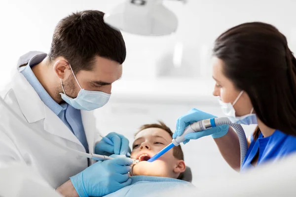 Dentista tratar dentes de criança na clínica odontológica — Fotografia de Stock