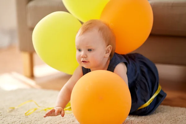 Mooie roodharige babymeisje met ballonnen thuis — Stockfoto