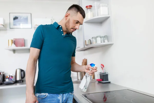 Człowiek z spray sprzątanie kuchenka w domowej kuchni — Zdjęcie stockowe