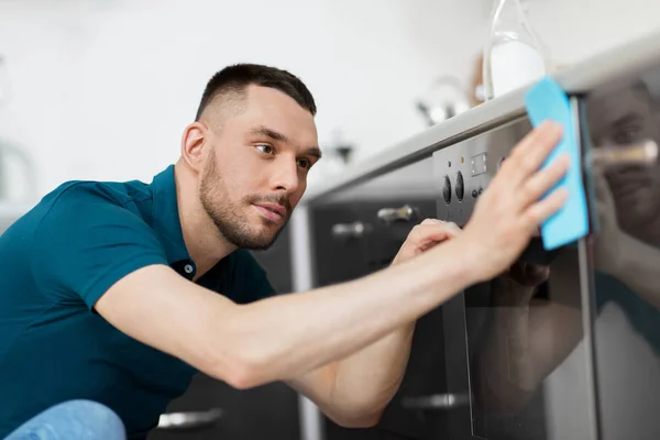 Homme avec chiffon nettoyage four porte à la maison cuisine — Photo