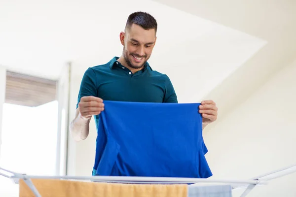 Smiling man with laundry and drying rack at home — Stock Photo, Image