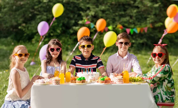 Gelukkige jonge geitjes met cake op verjaardag partij op de zomer — Stockfoto