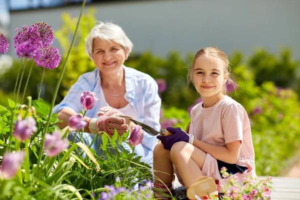 grandmother and girl planting flowers at garden