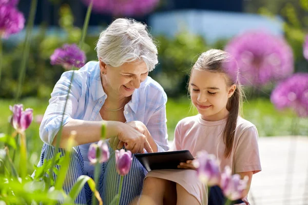 Babcia i dziewczyna z komputera typu tablet w ogrodzie — Zdjęcie stockowe