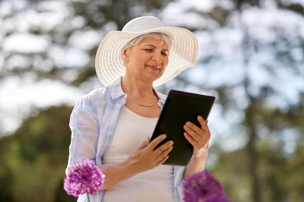 태블릿 pc와 꽃 정원에서 고위 여자 — 스톡 사진