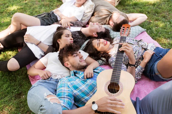 Друзья с гитарным охлаждением на одеяле для пикника — стоковое фото