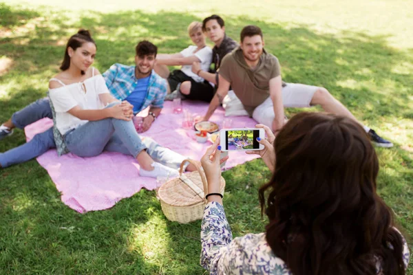 Woman picturing friends by smartphone at picnic — Stock Photo, Image