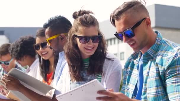Grupo de estudantes felizes com cadernos no campus — Vídeo de Stock