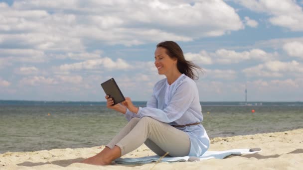 Heureuse femme souriante avec tablette PC sur la plage d'été — Video