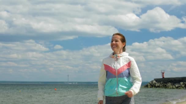 Lachende vrouw loopt langs het strand — Stockvideo