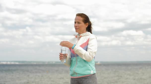 Mujer beber agua después de hacer ejercicio en la playa — Vídeos de Stock