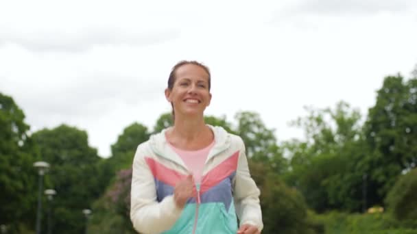 Sorrindo mulher correndo ao longo do parque — Vídeo de Stock