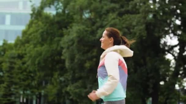 Uśmiechnięta kobieta, biegnącej wzdłuż parku — Wideo stockowe
