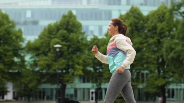 Smiling woman running along park — Stock Video