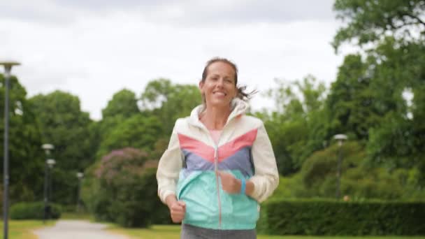 Kvinna med fitness tracker körs i park — Stockvideo