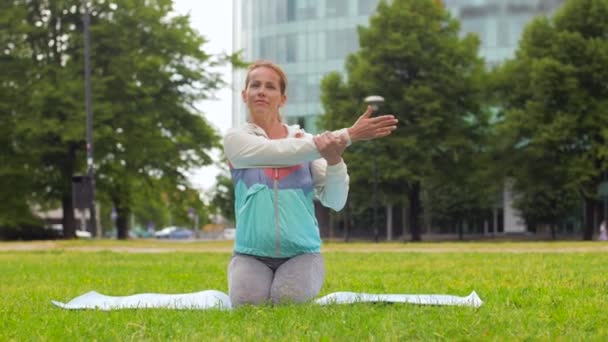 Kvinna som utövar på yogamatta på park — Stockvideo