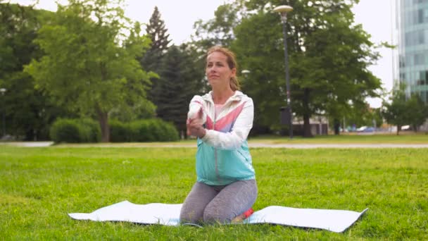 Женщина упражняется на коврике для йоги в парке — стоковое видео