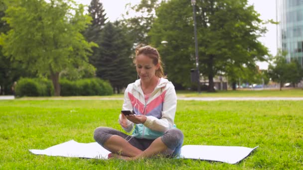 Frau mit Smartphone legt Musik für Meditation auf — Stockvideo