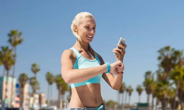 Szczęśliwa kobieta z fitness tracker i smartphone — Zdjęcie stockowe