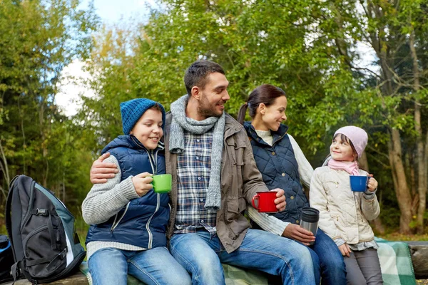 Familia feliz con tazas de té caliente en el campamento — Foto de Stock