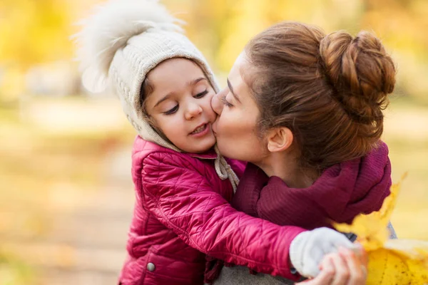 Mutter küsst kleine Tochter im Herbst — Stockfoto