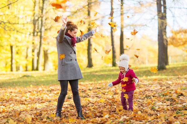 Familia feliz jugando con hojas de otoño en el parque — Foto de Stock