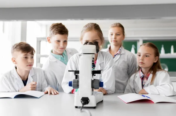 Barn eller elever med mikroskopet biologi i skolan — Stockfoto