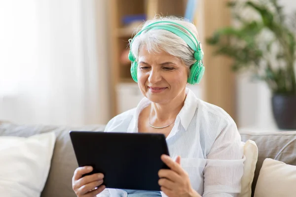 Starší žena ve sluchátkách poslouchat hudbu — Stock fotografie