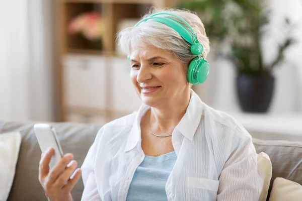 Femme âgée dans les écouteurs écouter de la musique — Photo