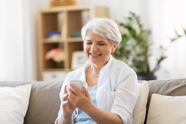 Felice donna anziana con smartphone a casa — Foto Stock