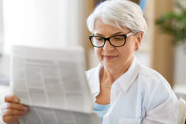 Portrait of senior woman reading newspaper at home — Stock Photo, Image