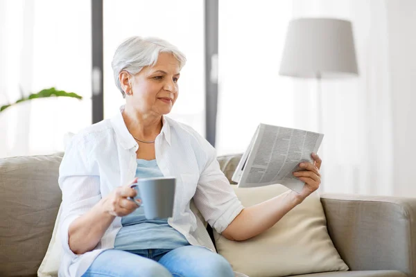 Старша жінка з газетою для читання кави вдома — стокове фото