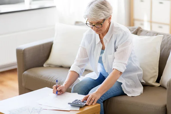 Seniorin mit Papieren und Taschenrechner zu Hause — Stockfoto