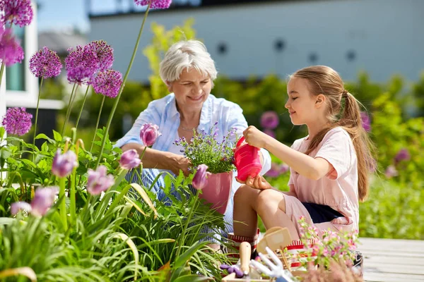 Babička a dívka sázel květiny na zahradě — Stock fotografie