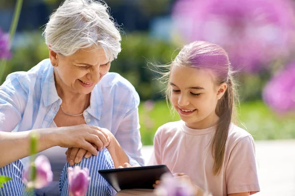 Oma en meisje met tablet pc bij tuin — Stockfoto