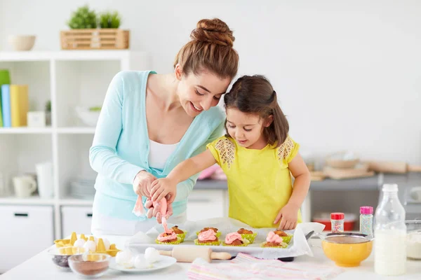 母亲和女儿在家里做纸杯蛋糕 免版税图库照片
