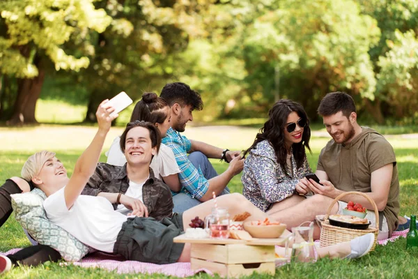 Freunde mit Smartphones beim Picknick im Sommerpark — Stockfoto