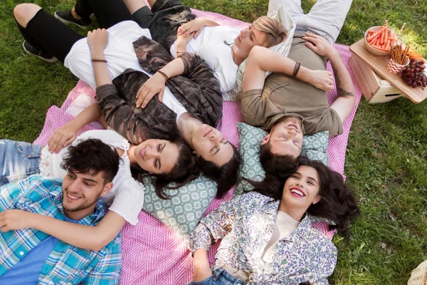 Amigos felices escalofriantes en manta de picnic en verano — Foto de Stock