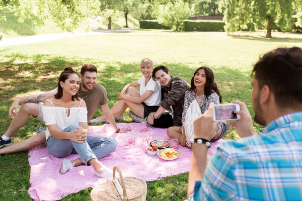 Uomo fotografare gli amici da smartphone al picnic — Foto Stock