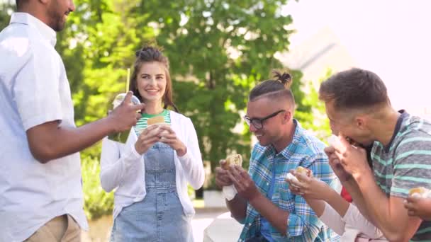 Přátelé jíst sendviče a mluví v parku — Stock video