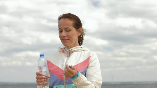 Frau trinkt Wasser nach Sport am Strand — Stockvideo