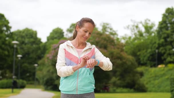 Kobieta z fitness tracker działa w parku — Wideo stockowe