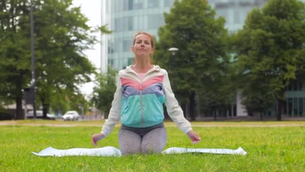 Kvinna som utövar på yogamatta på park — Stockvideo