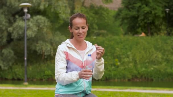 女性は、公園で運動した後の水を飲む — ストック動画