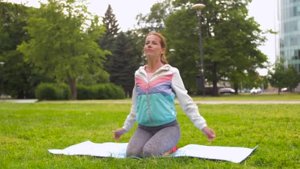 Kvinna som utövar på yogamatta på park — Stockvideo