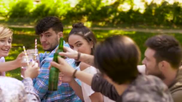 Glada vänner spottar drycker på sommaren park — Stockvideo