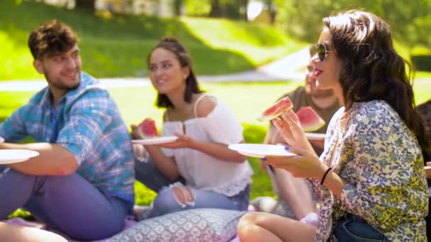 Счастливые друзья едят арбуз на летнем пикнике — стоковое видео