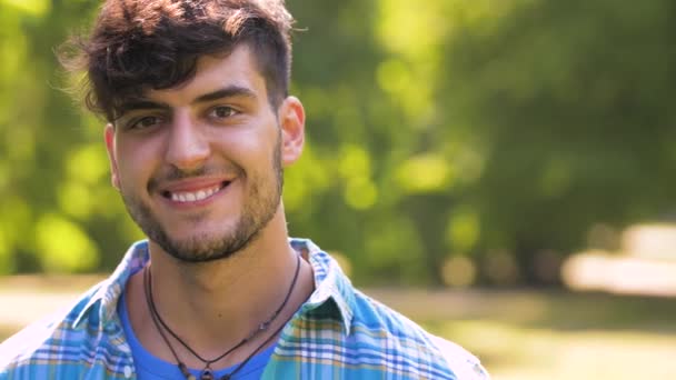 Портрет усміхненого молодого чоловіка в літньому парку — стокове відео